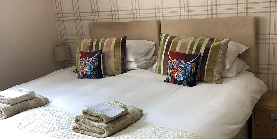 Ardmorn Double Bedroom with check wallpaper and highland cow cushions
