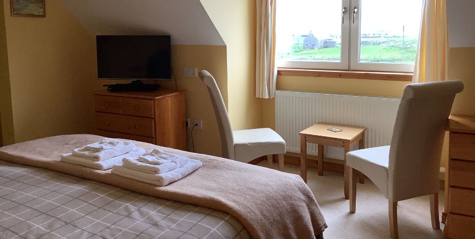 Rowan Tree, North Uist, double bedroom withtable and chair in front of parge window.