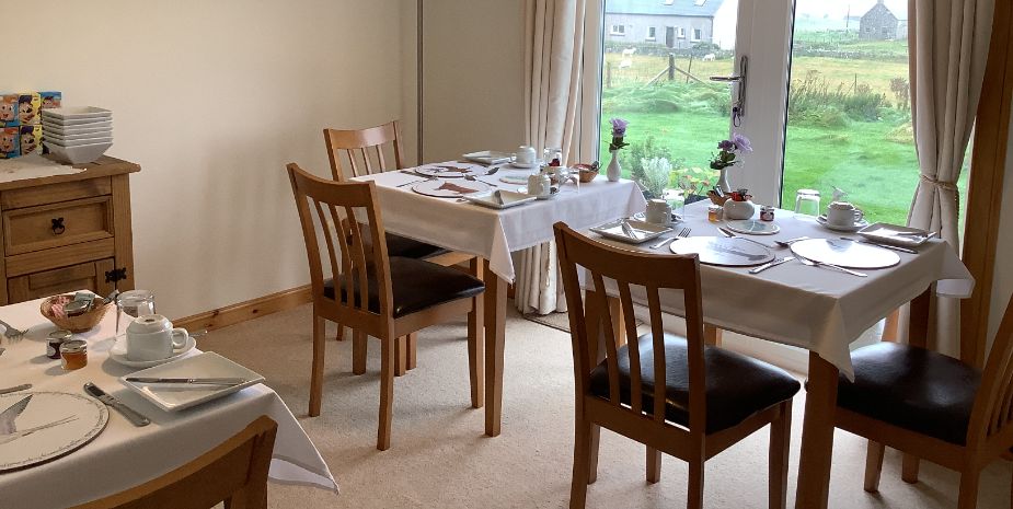 Rowan Tree, North Uist, Dining room with tables and chairs set for breakfast, double doors looking out to garden.