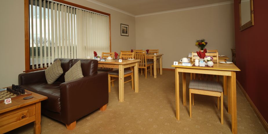 Borve Guesthouse Dining Room with wooden tables and chairs set for breakfast.