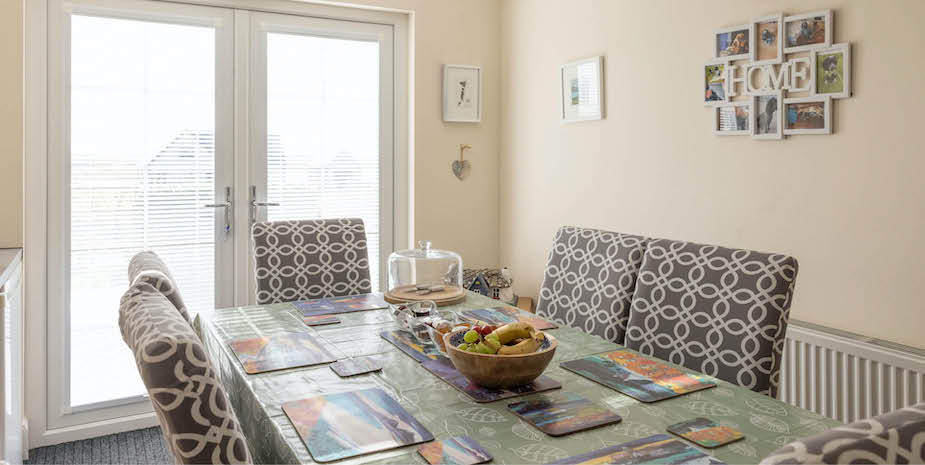 A bright dining room at Ard Buidhe B&B featuring a table and chairs, with large double doors letting in natural light.