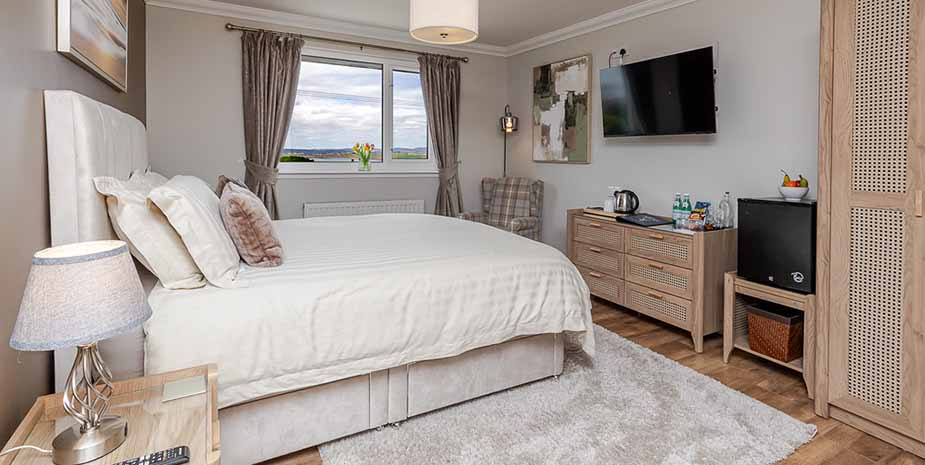 Bright and spacious bedroom at Seaview B&B featuring a large bed, wall mounted tv and stunning sea views.
