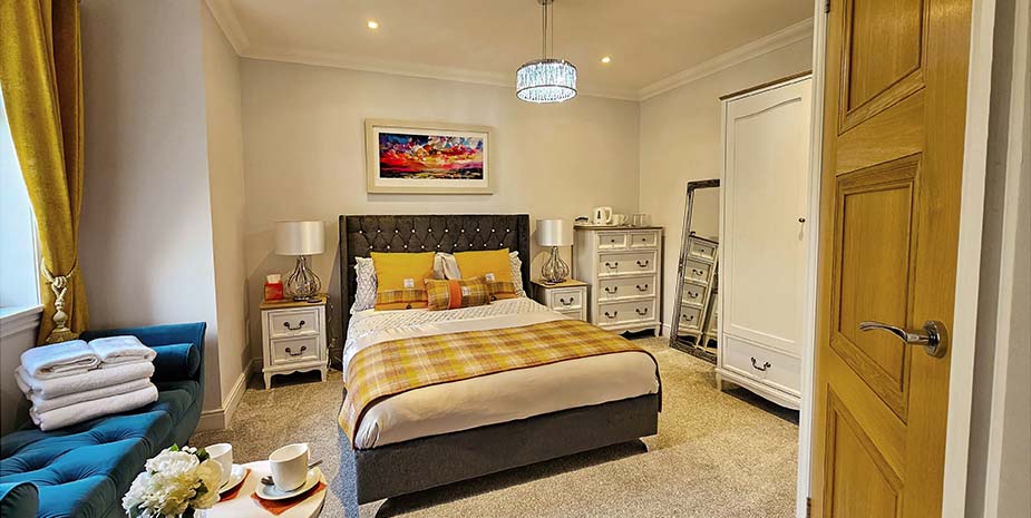 Cosy double room at Sranndabhal B&B, featuring a bed, dressing table, and a chaise longue in a warm, inviting setting.
